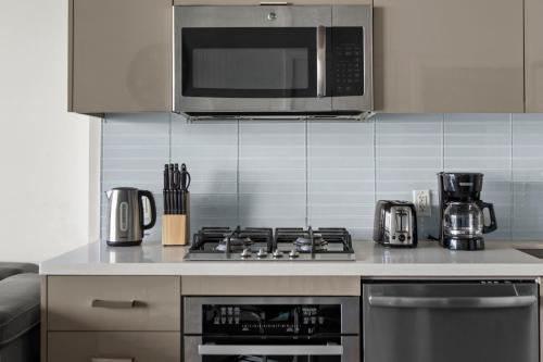 a kitchen with a stove and a microwave at GLOBALSTAY Downtown Calgary Apartments in Calgary
