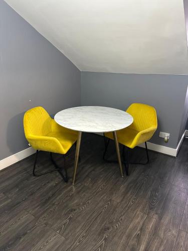 a table and two yellow chairs in a room at Quiet Top-Floor Retreat -Modern Studio for 2 - Islington in London