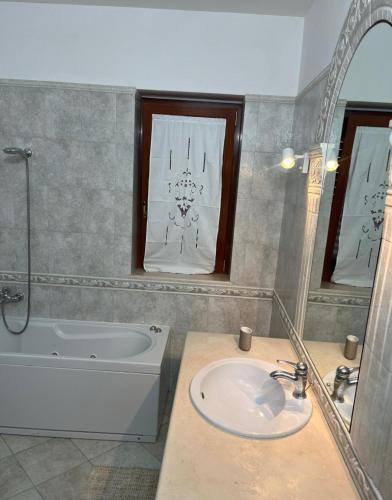 Un baño con lavabo, bañera y espejo. en House in Cave, en Massafra