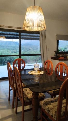 a dining room table with chairs and a large window at Sol & Río Refugio Serrano in Villa Las Rosas