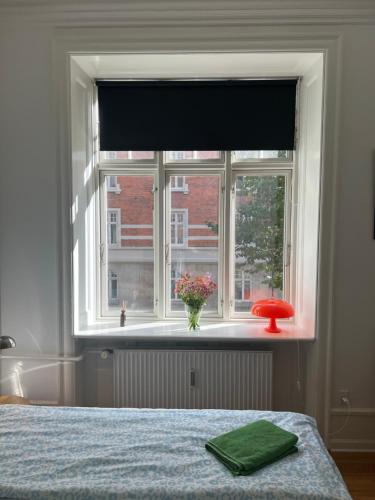 a bedroom with a window with a vase of flowers at Topcity in Copenhagen