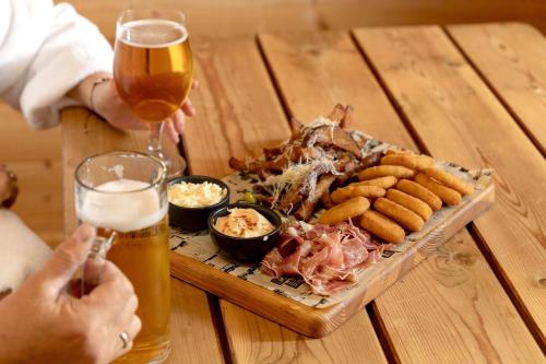 a table with a plate of food and a glass of beer at Butenas Hotel Tyla in Biržai