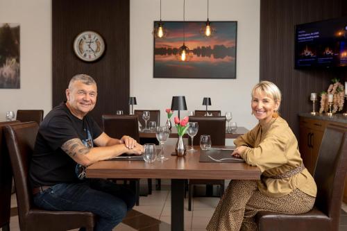 a man and woman sitting at a table in a restaurant at Butenas Hotel Tyla in Biržai
