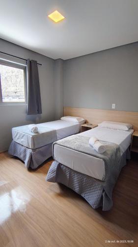 two beds in a room with a window at Unity Hotel - Allianz SP in São Paulo