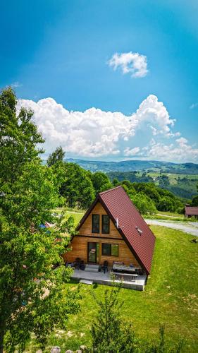 a log cabin with a red roof on a green field at Cabana Arunia in Buninginea