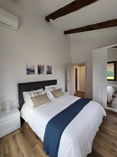 a bedroom with a large white bed with a blue blanket at Residenze La Barchessa in Santo Stefano di Zimella