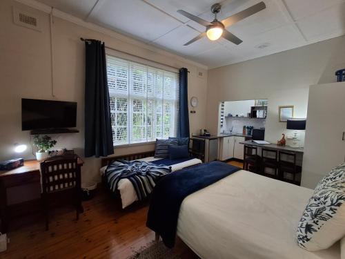 a bedroom with two beds and a desk and a window at Apartment 7 On Oakleigh in Pietermaritzburg
