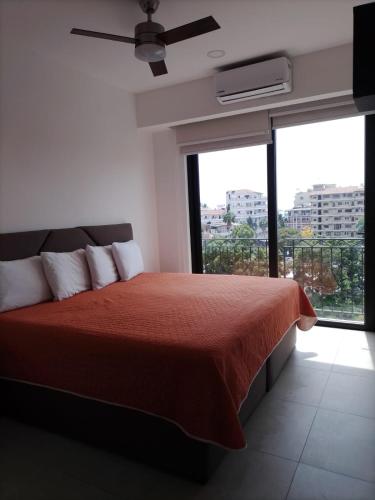 a bedroom with a red bed and a large window at Central Studio with Roof Top Romantic Zone 202 in Puerto Vallarta