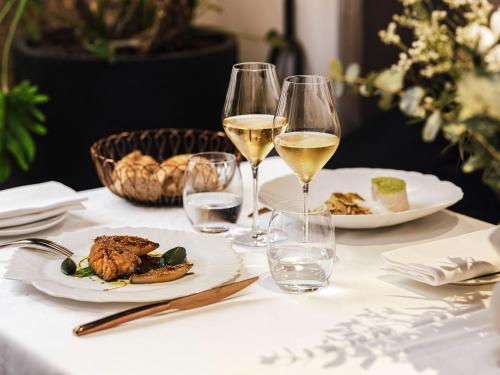 a table with two glasses of white wine and food at Balthazar Hotel & Spa Rennes - MGallery Collection in Rennes