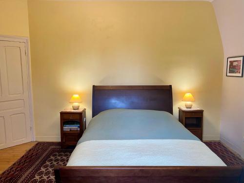 a bedroom with a bed and two night stands with lamps at B&B Manoir de Keryvon in Saint-Derrien