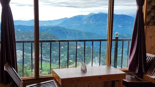 a room with a table and a view of mountains at Hotel HiLL Mount View Dalhousie Chamba in Dalhousie