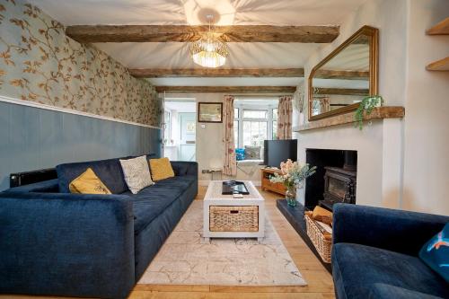 a living room with a blue couch and a fireplace at Quaint 200 year old cosy characterful cottage in Swanland