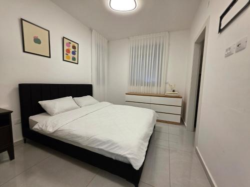 a bedroom with a bed with white sheets and a window at Hantke22• Horev Penthouse • Jacuzzi • 4BD in Aẖuzzat Shemu‘el