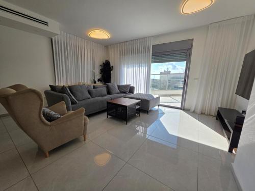 a living room with a couch and a table at Hantke22• Horev Penthouse • Jacuzzi • 4BD in Aẖuzzat Shemu‘el