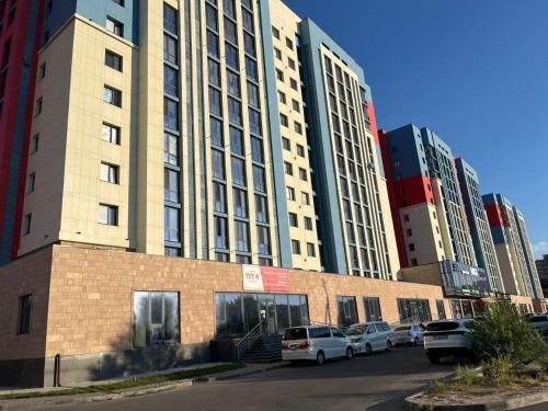 a tall building with cars parked in front of it at Уютная, стильная люх квартира в городе Шымкент in Shymkent