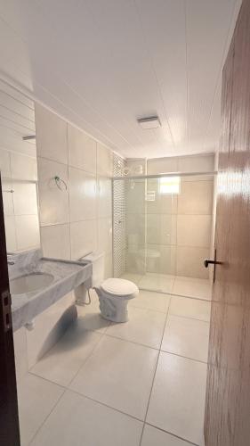 a bathroom with a toilet and a glass shower at Pousada Casa Silva in Maceió