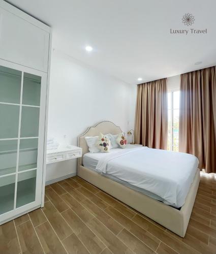 a bedroom with a white bed and a large mirror at Villa NovaWorld Phan Thiết garden view, 3 BR for 6-8pax in Bình Tú