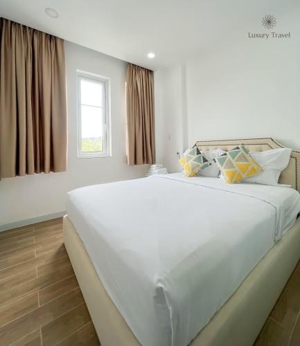 a large white bed in a room with a window at Villa NovaWorld Phan Thiết garden view, 3 BR for 6-8pax in Bình Tú