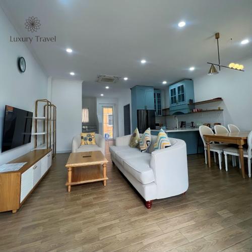 a living room with a white couch and a kitchen at Villa NovaWorld Phan Thiết garden view, 3 BR for 6-8pax in Bình Tú