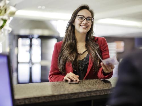 a woman with glasses sitting at a counter at Novotel Queenstown Lakeside in Queenstown