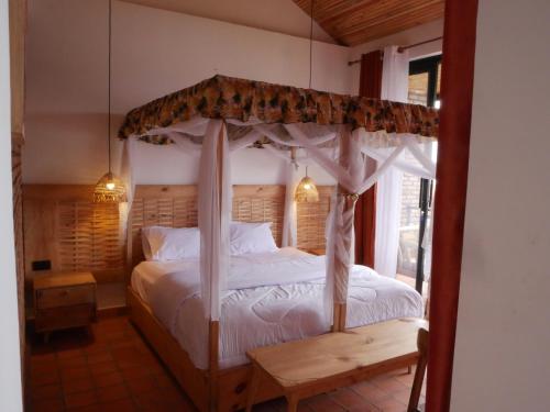 Un dormitorio con una cama con dosel y una ventana. en Muhazi Dolce Vita Ecolodge, 
