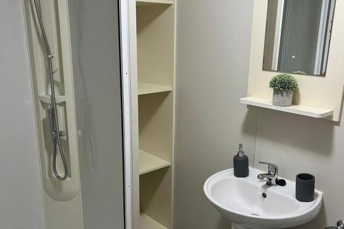 a white bathroom with a sink and a shower at 3 Bedroom Caravan - Sleeps 8 - Parking Wifi Pool in Clacton-on-Sea