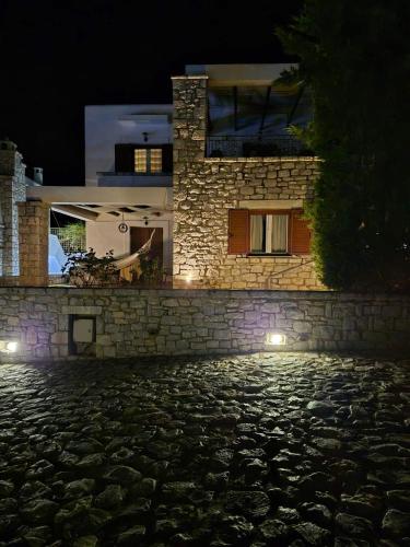 a house with lights on a stone wall at night at Malvazios Villas #5 in Gythio