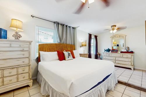 Un dormitorio con una cama blanca y una cómoda. en Mesquite House Upstairs Unit, en South Padre Island