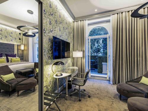 a hotel room with a bed and a table and chairs at Mercure London Hyde Park Hotel in London