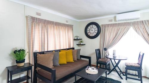 a living room with a couch and a table and a clock at High Court Self Catering Apartments in Nelspruit