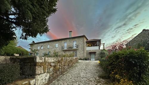 an old stone house with a rainbow in the sky at Casa De Fatauncos in Vouzela