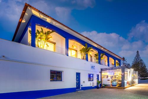 a large white building with blue accents at Alojamento Costa Alentejana in Zambujeira do Mar