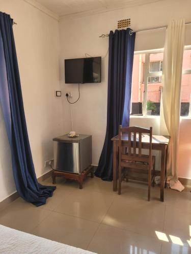 a bedroom with blue curtains and a table and a chair at Guestmate Inn in Livingstone