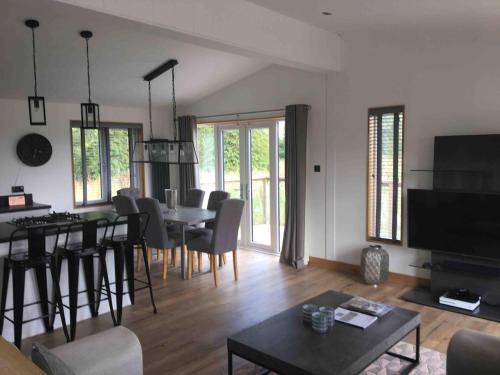 a living room with a table and a dining room at Contemporary 3 bed luxury Spa lodge with hot tub in Bury Saint Edmunds