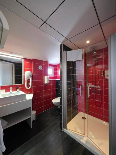 a bathroom with red walls and a shower and a sink at Logis Hotel Restaurant Le Grand Turc in LʼOie