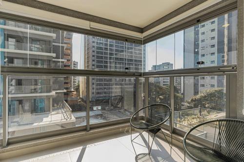 a balcony with two chairs and a view of the city at Colibri -ZCotovia Luxo e Aconchego in Sao Paulo
