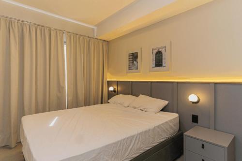 a small bedroom with a white bed and two lights at Colibri -ZCotovia Luxo e Aconchego in Sao Paulo