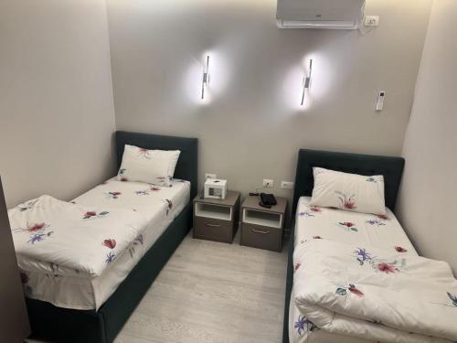 two beds in a room with white walls at London Restaurant Hotel in Kukës
