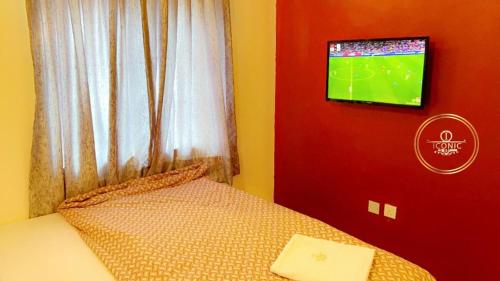 a bedroom with a bed with a tv on the wall at Iconic Hotel and Lounge in Alagbado
