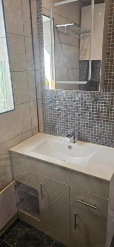 ein Badezimmer mit Waschbecken und Spiegel in der Unterkunft Cosy Studio Quest House in Romford