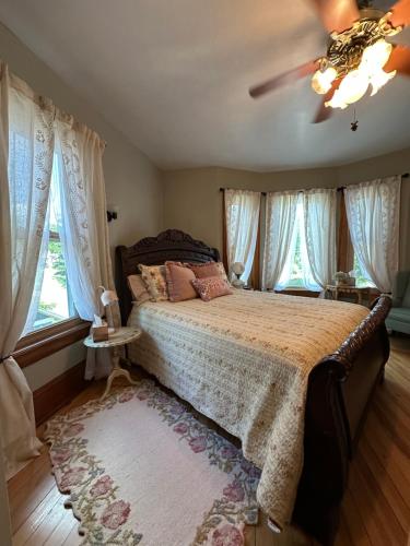 a bedroom with a large bed with curtains and a ceiling fan at The Rest Is History in Baraboo