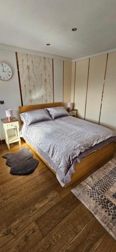 a bedroom with a large bed and a clock on the wall at Cosy Studio Quest House in Romford