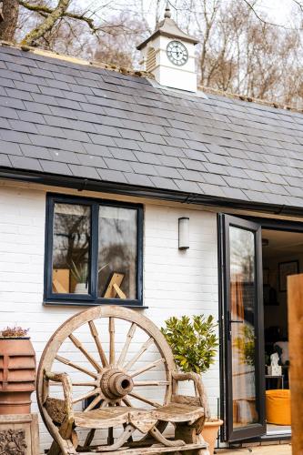 a building with a clock tower and a wooden wagon wheel at Ashdown Forest Retreat in Nutley
