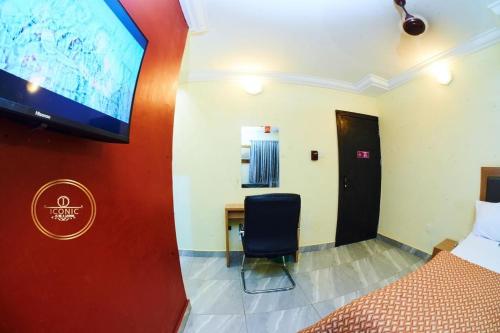 a room with a bed and a desk and a tv at Iconic Hotel and Lounge in Alagbado
