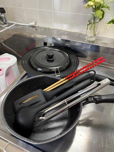 a frying pan with tongs in a pan on a stove at Stay Chacha 城下町茶茶2F in Marugame