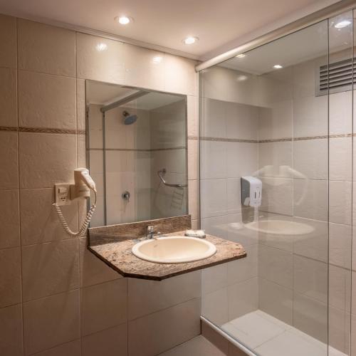 a bathroom with a sink and a shower with a phone at Golden Beach Resort & Spa in Punta del Este