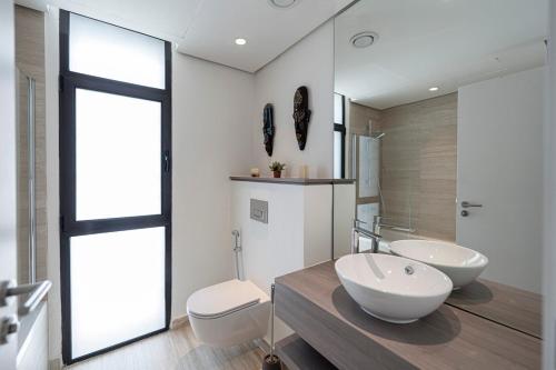 a bathroom with two sinks and a toilet at Ayla Oasis Golf Apartment - Ayla Vista in Aqaba