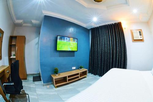 a bedroom with a bed and a tv on a blue wall at Iconic Hotel and Lounge in Alagbado