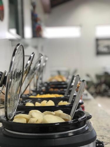 a row of trays of food on a counter at Hotel Trevo Caruaru in Caruaru