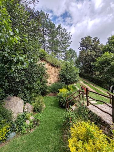 a garden with a wooden fence and grass and trees at Finca Chuchiyá cabañas Tecpan in Tecpán Guatemala